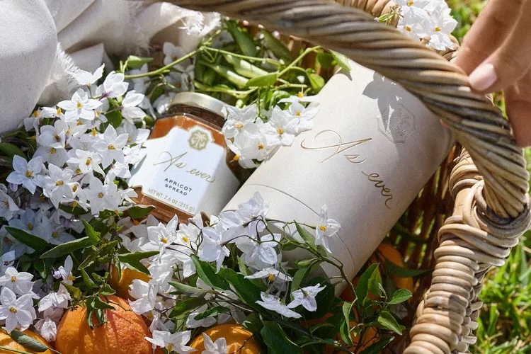As Ever by Meghan Markle luxury picnic basket featuring apricot fruit spread, white floral accents, and elegant seasonal packaging in a rustic wicker basket — ideal for spring entertaining, artisanal food lovers, and modern lifestyle branding.
